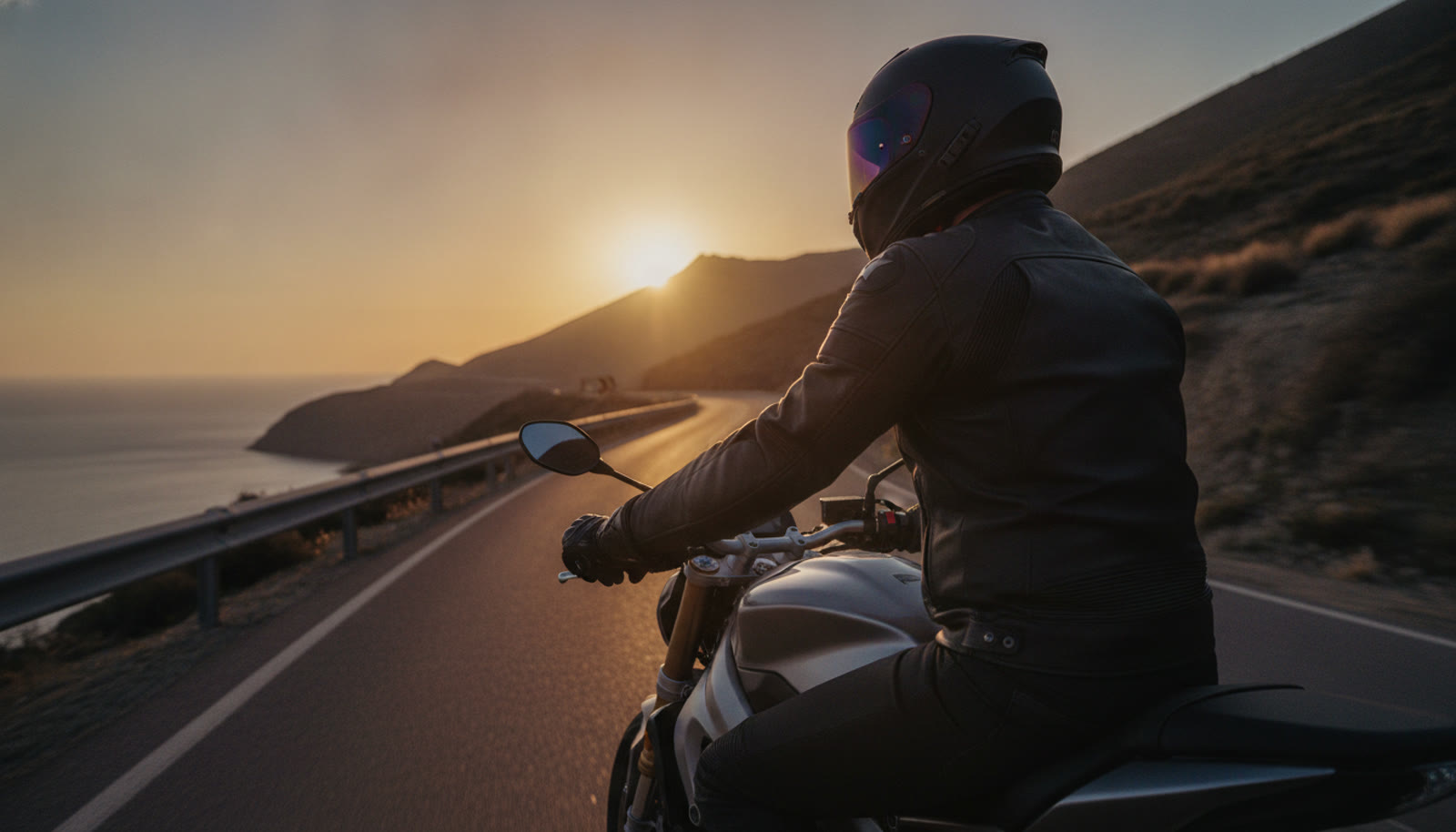 Motero fluyendo por una carretera de costa al atardecer